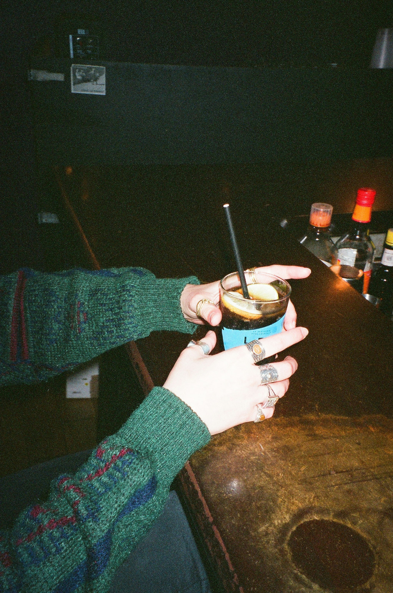 Une personne tient un verre au comptoir d'un bar